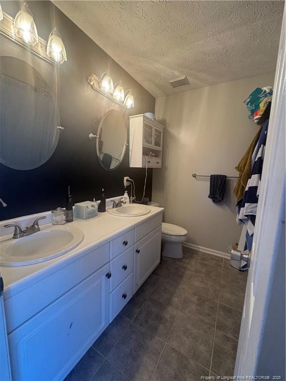 bathroom with tile patterned flooring, visible vents, double vanity, and a sink