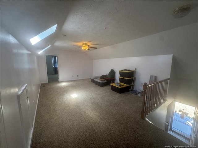 bonus room featuring vaulted ceiling with skylight, a textured ceiling, and carpet floors