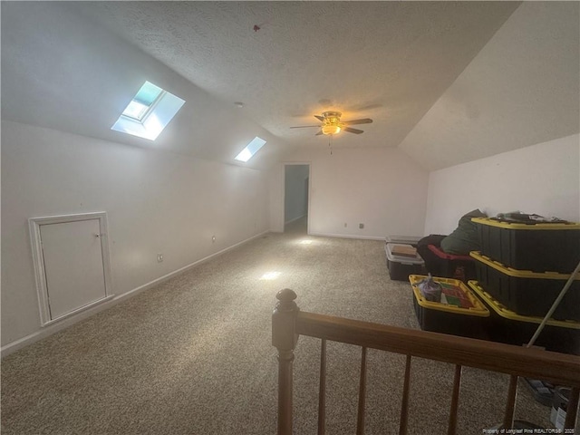 additional living space featuring lofted ceiling with skylight, carpet flooring, a textured ceiling, and baseboards