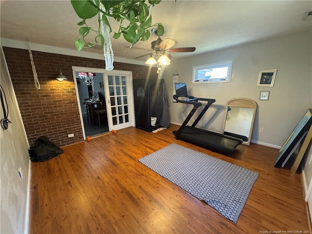 workout room featuring brick wall, ceiling fan, and wood finished floors