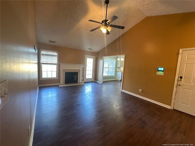 unfurnished living room with plenty of natural light, baseboards, dark wood-style flooring, and ceiling fan