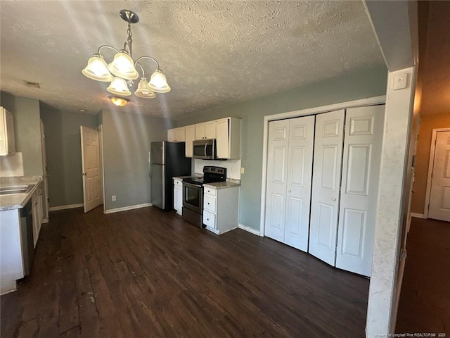 kitchen with appliances with stainless steel finishes, white cabinets, light countertops, a chandelier, and dark wood-style flooring