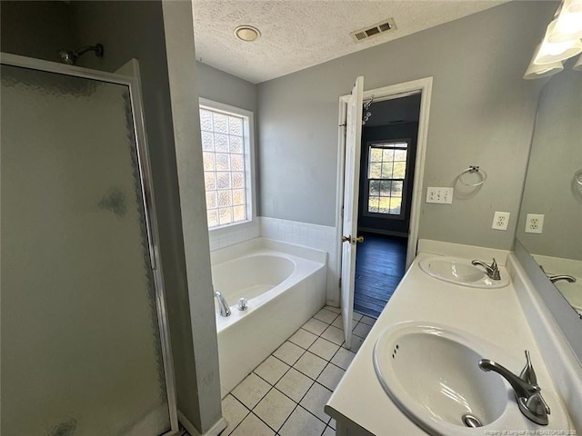 full bathroom with tile patterned flooring, a stall shower, visible vents, and a sink