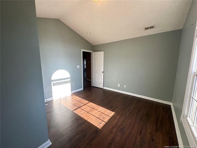 unfurnished room featuring visible vents, a textured ceiling, wood finished floors, baseboards, and lofted ceiling