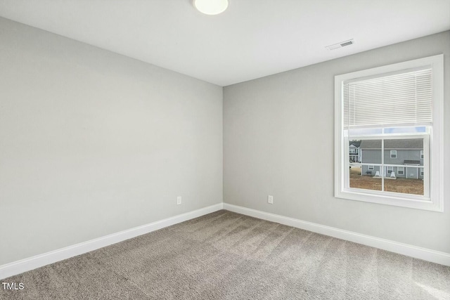 carpeted spare room with visible vents and baseboards