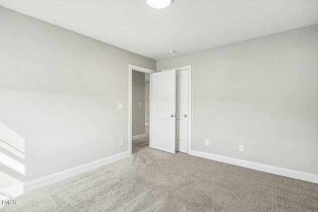 spare room with baseboards and carpet floors