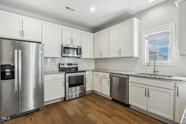 kitchen featuring visible vents, dark wood-style flooring, a sink, stainless steel appliances, and white cabinets