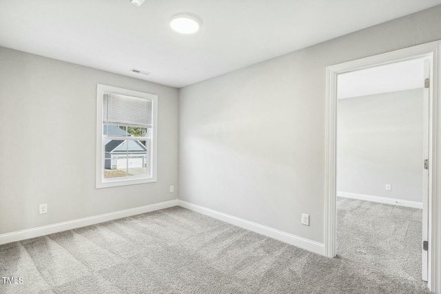 carpeted spare room with visible vents and baseboards