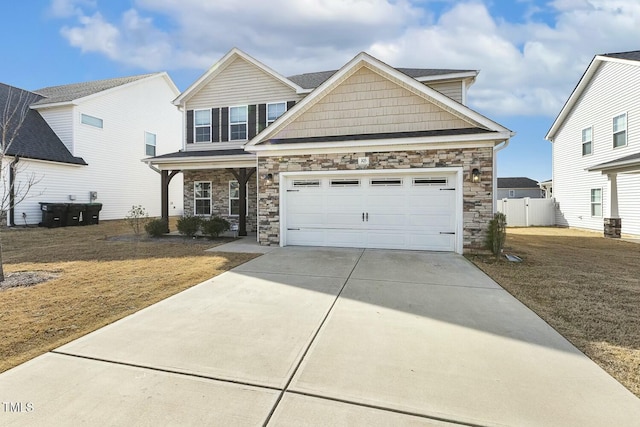 view of front of property with a front lawn, driveway, stone siding, fence, and an attached garage