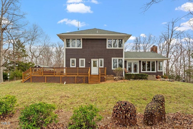 back of property with a deck, a yard, roof with shingles, and a chimney