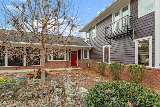 view of front of home featuring a balcony and brick siding