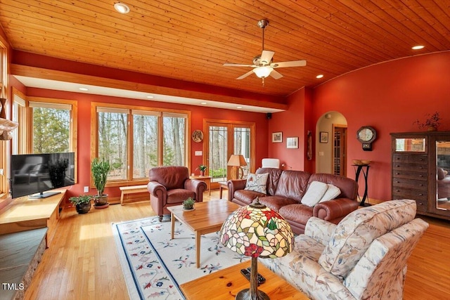 living room featuring arched walkways, a healthy amount of sunlight, and wood finished floors