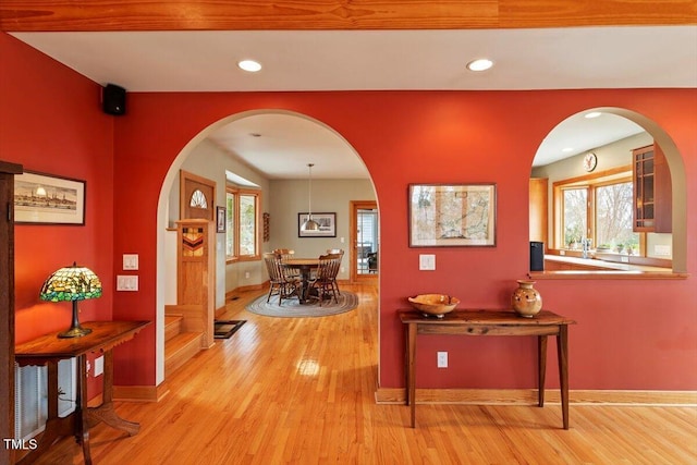 corridor with recessed lighting, wood finished floors, baseboards, and arched walkways