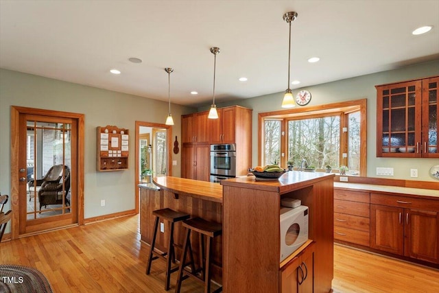 kitchen featuring white microwave, recessed lighting, light wood-style flooring, and double oven