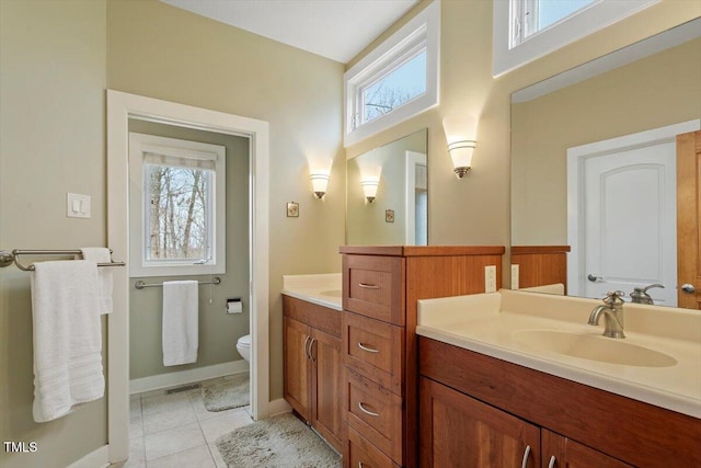 bathroom with tile patterned flooring, vanity, toilet, and a healthy amount of sunlight