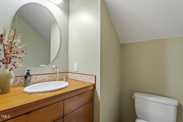 half bath featuring toilet, vanity, and vaulted ceiling