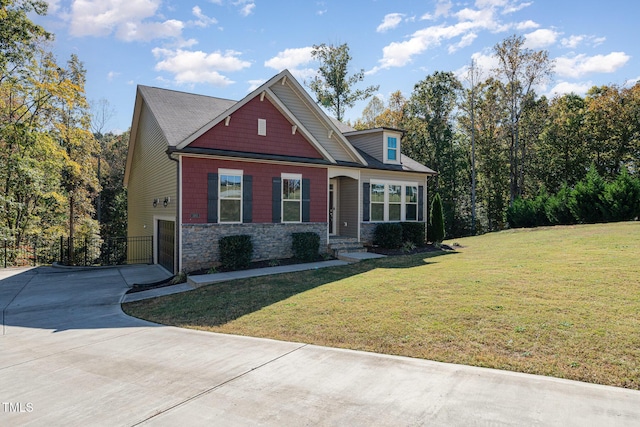 craftsman-style home featuring stone siding, concrete driveway, a front yard, and fence