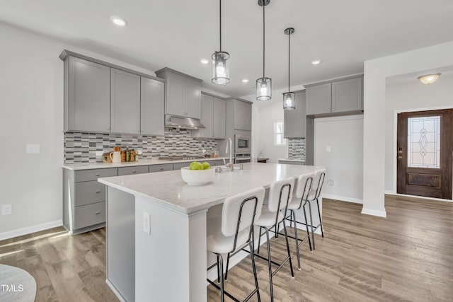 kitchen featuring under cabinet range hood, tasteful backsplash, appliances with stainless steel finishes, and gray cabinets