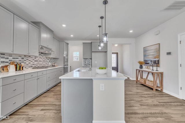 kitchen with under cabinet range hood, visible vents, gray cabinets, and a sink