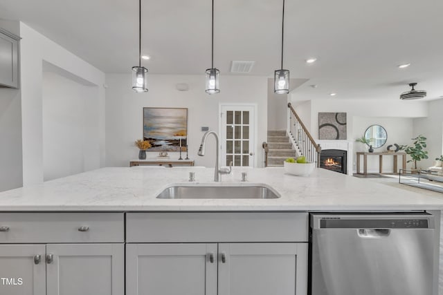 kitchen with visible vents, open floor plan, dishwasher, a glass covered fireplace, and a sink