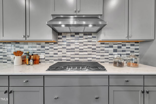 kitchen featuring ventilation hood, backsplash, gray cabinetry, and stainless steel gas stovetop