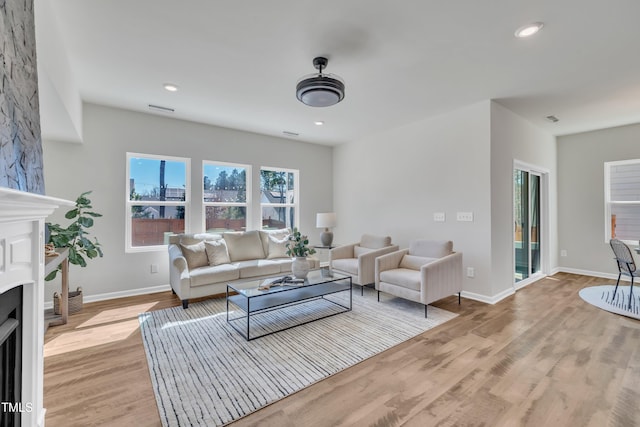 living area featuring light wood finished floors, recessed lighting, a fireplace, and baseboards