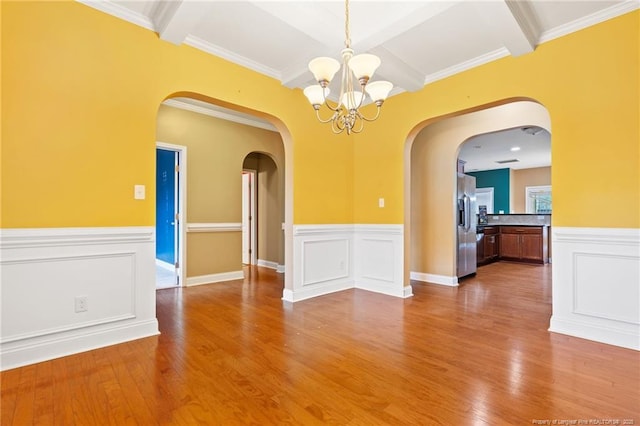 unfurnished room featuring beamed ceiling, a notable chandelier, wood finished floors, and arched walkways