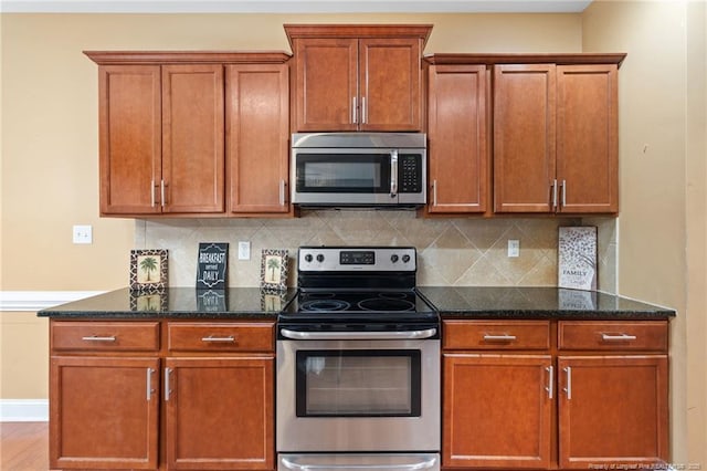 kitchen featuring backsplash, stainless steel appliances, and dark stone countertops