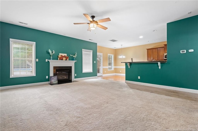 unfurnished living room with visible vents, a fireplace with flush hearth, baseboards, and a ceiling fan