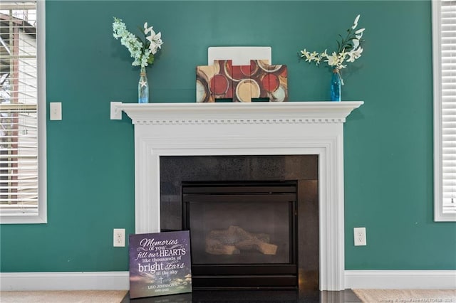 interior details with a glass covered fireplace and baseboards