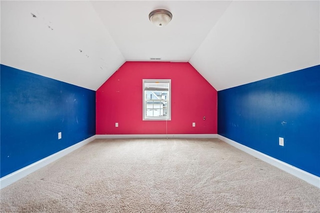 additional living space with baseboards, visible vents, lofted ceiling, and carpet floors