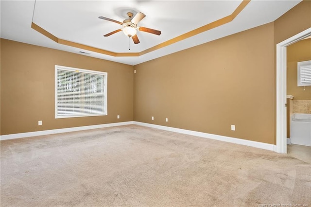 unfurnished room with baseboards, a raised ceiling, light colored carpet, and visible vents