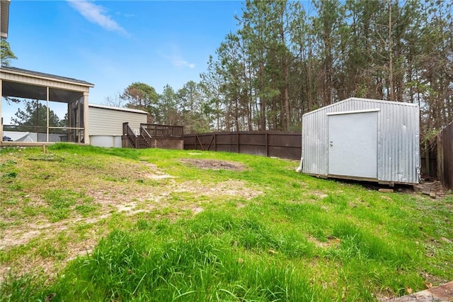 view of yard with an outdoor structure, a storage shed, a fenced backyard, and a sunroom