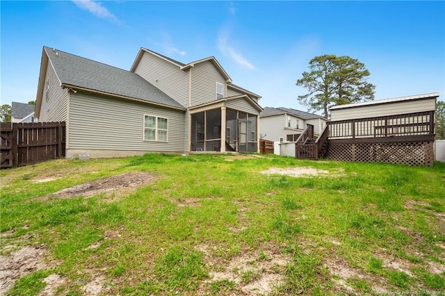 rear view of property featuring a yard, fence, a wooden deck, and a sunroom