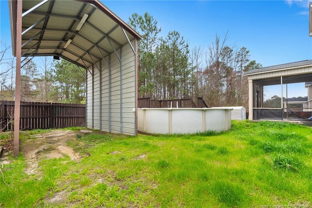 view of yard with a detached carport, a fenced in pool, a sunroom, and fence