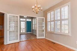 doorway to outside featuring a chandelier, french doors, baseboards, and wood finished floors