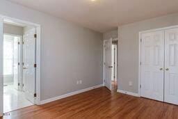 unfurnished bedroom with wood finished floors, baseboards, and a closet