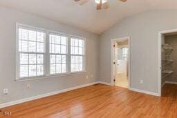 unfurnished bedroom featuring vaulted ceiling, wood finished floors, baseboards, and ensuite bathroom