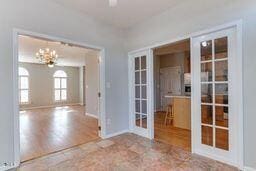 empty room featuring french doors, baseboards, an inviting chandelier, and wood finished floors