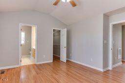 unfurnished bedroom featuring a walk in closet, lofted ceiling, wood finished floors, and a closet