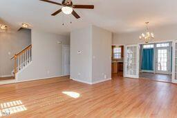 unfurnished living room featuring stairway, ceiling fan with notable chandelier, and wood finished floors