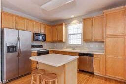 kitchen with light wood finished floors, a kitchen island, stainless steel appliances, and light countertops