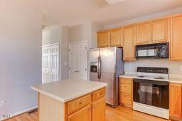 kitchen featuring electric range, light countertops, black microwave, stainless steel fridge, and a center island