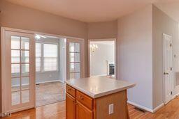 kitchen with brown cabinets, a center island, light wood-style floors, light countertops, and baseboards