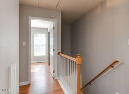 hall featuring baseboards, an upstairs landing, and wood finished floors