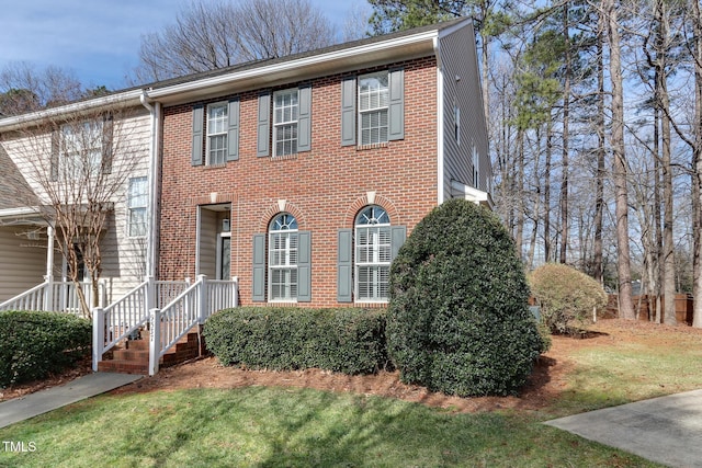 view of front facade with brick siding and a front yard