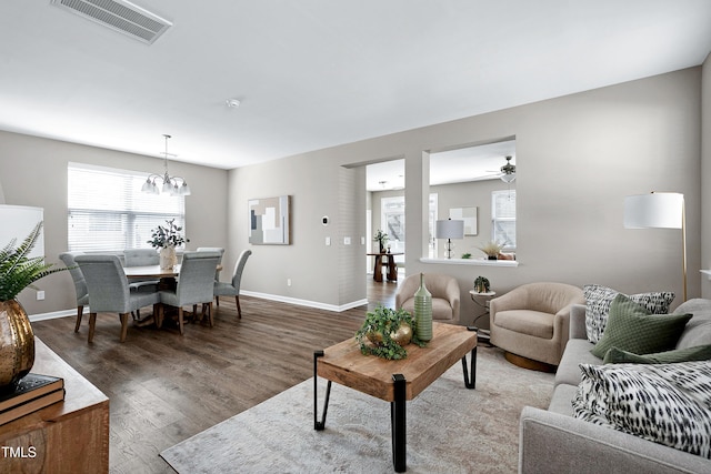 living room with visible vents, baseboards, wood finished floors, and a chandelier