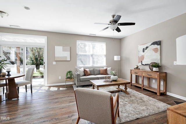 living room featuring visible vents, baseboards, dark wood finished floors, and a ceiling fan