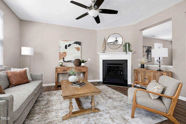 living room with a fireplace with flush hearth, baseboards, and wood finished floors