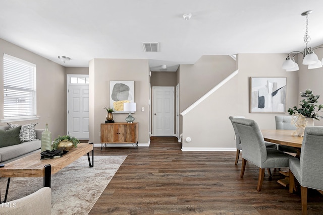 living room with dark wood-style floors, visible vents, baseboards, and an inviting chandelier